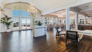 A spacious hotel lobby with high ceilings, large windows, and a central seating area.