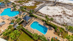 A resort with multiple swimming pools, a beach, and a boardwalk.