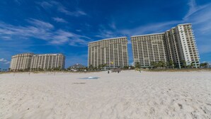 A beachfront hotel with multiple high-rise buildings, sandy beach, and clear blue sky.