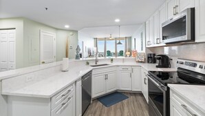 A modern kitchen with white cabinets, a built-in oven, and a microwave.
