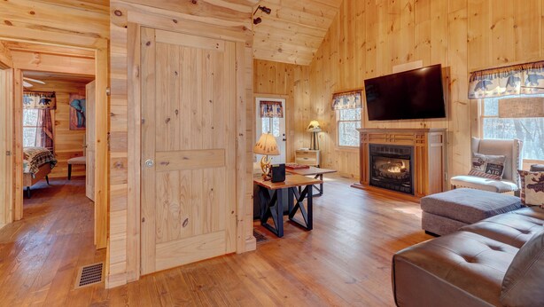 Un interior de madera con chimenea, televisor y sofá.