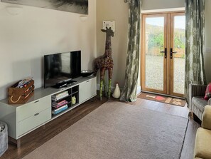 A living room with a television, books, a giraffe statue, and a sliding glass door leading to an outdoor area.