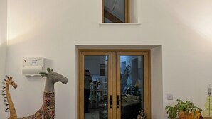 Una habitación con una puerta de madera, una ventana pequeña encima y una decoración de jirafa en la pared.