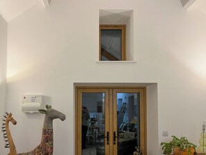 A room with a wooden door, a small window above it, and a giraffe decoration on the wall. - 1 bedroom accommodation in Holsworthy (Holsworthy)