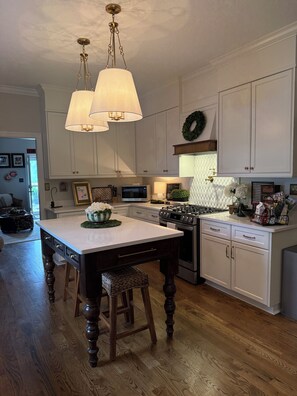 A kitchen with a central island, wooden flooring, white cabinetry, and pendant lighting. - Masters Rental - Augusta, Ga. 1/2 mile from Augusta National (Augusta)