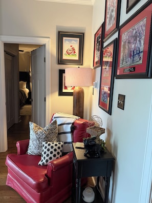 A red leather armchair with polka dot and striped throw pillows, a black side table with a decorative object, and framed pictures on the wall. - Masters Rental - Augusta, Ga. 1/2 mile from Augusta National (Augusta)