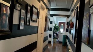 Un pasillo con paredes a rayas negras y blancas, cuadros enmarcados y suelo de madera.