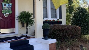 Una casa con puerta roja, una bandera amarilla y un pequeño porche con escalones que conducen a la entrada.