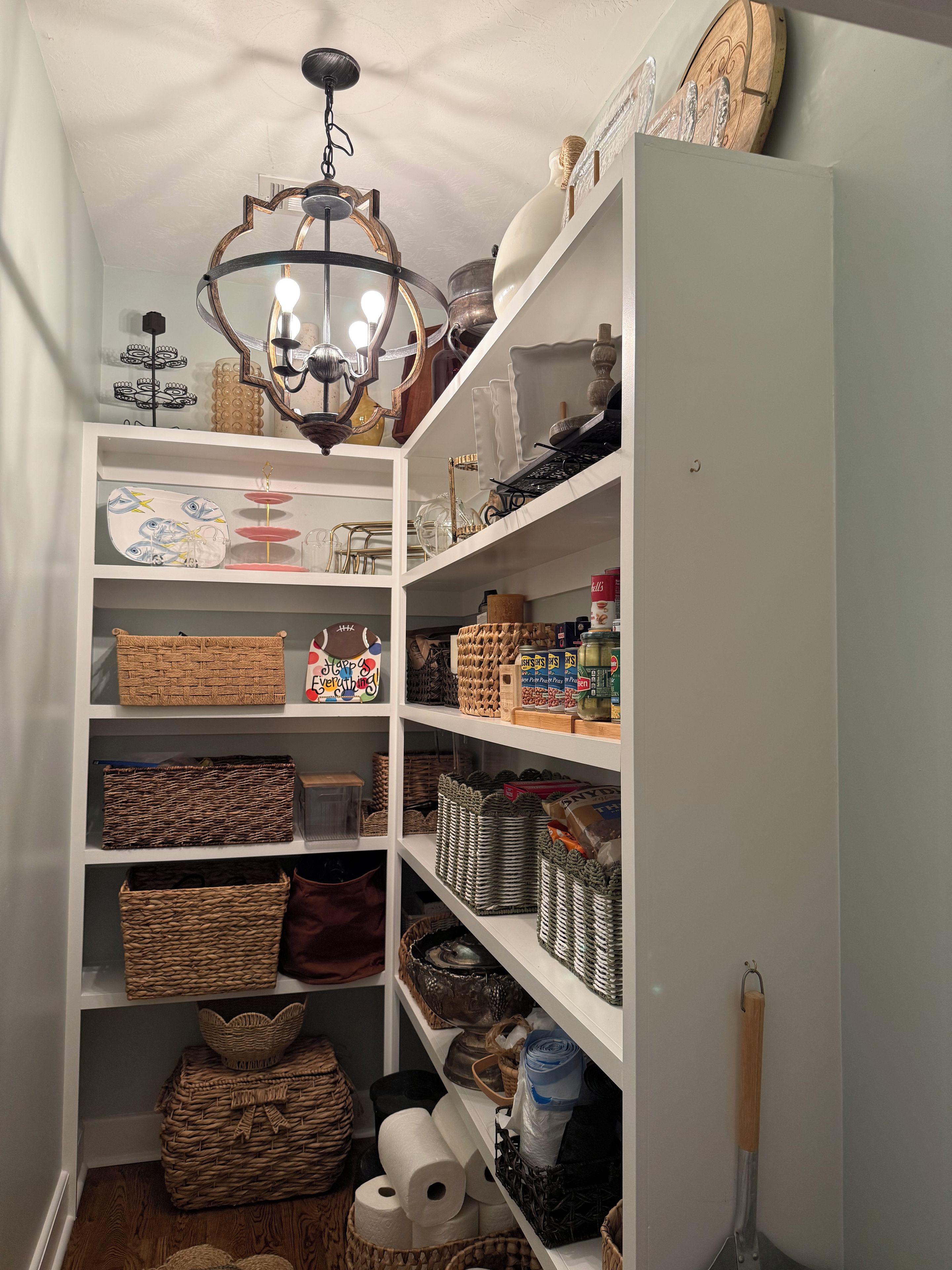 A well-organized storage room with shelves containing baskets, jars, and household items.