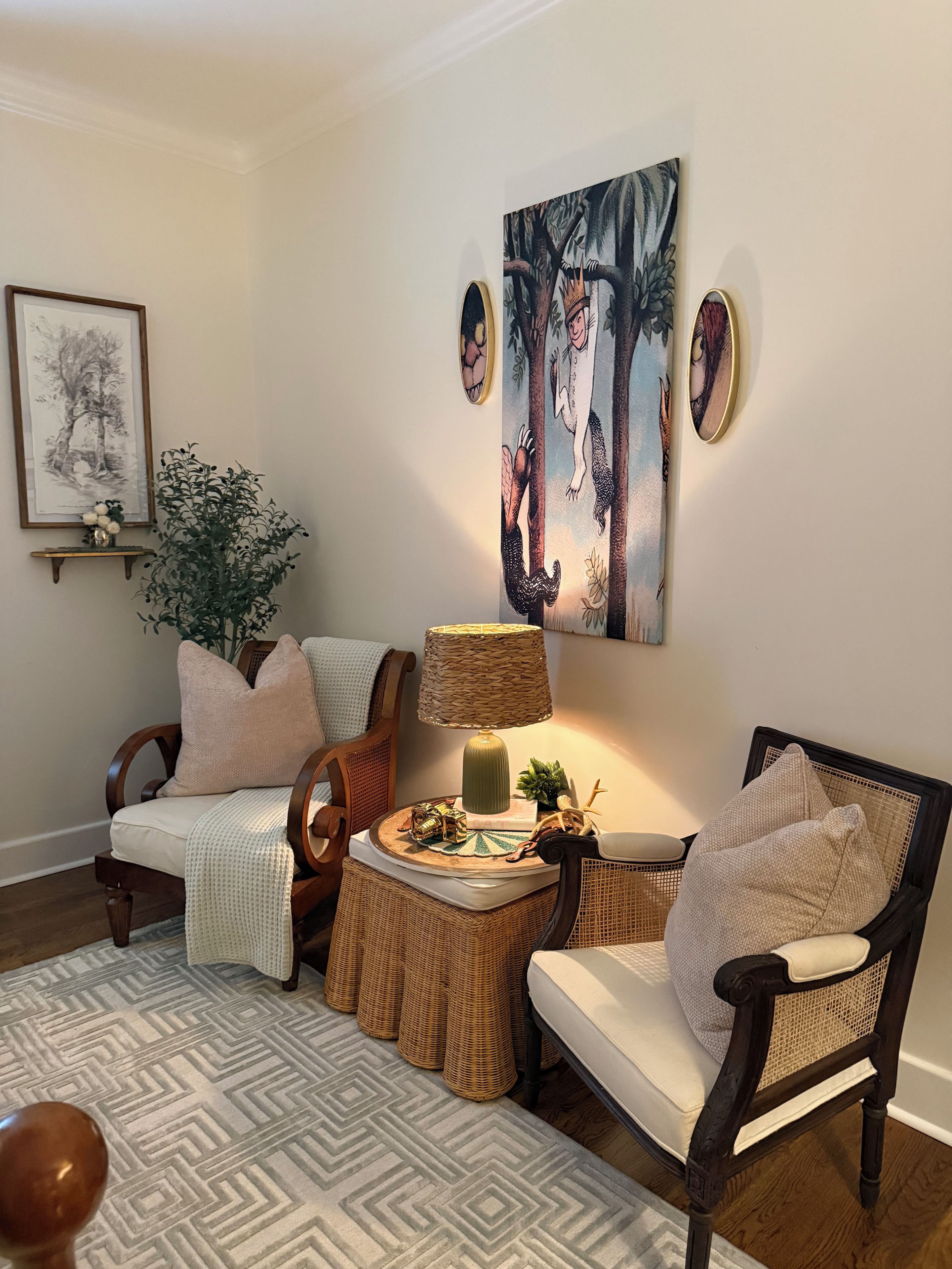 A cozy living room with a sofa, chairs, a coffee table, and a lamp. There are wall art pieces and a potted plant.