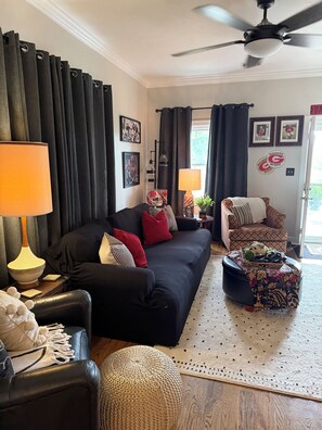 A living room with a black sofa, a coffee table, a lamp, and a ceiling fan. - Masters Rental - Augusta, Ga. 1/2 mile from Augusta National (Augusta)