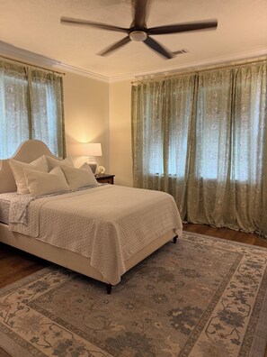 A bedroom with a bed, a ceiling fan, curtains, a nightstand, and a rug. - Masters Rental - Augusta, Ga. 1/2 mile from Augusta National (Augusta)