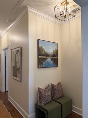 A hallway with a green bench, a painting of a landscape, and a ceiling light fixture. - Masters Rental - Augusta, Ga. 1/2 mile from Augusta National (Augusta)
