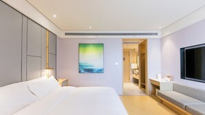 Een moderne hotelkamer met een groot bed, een televisie, een schilderij en een inloopkast.
