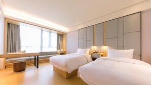 Een hotelkamer met twee bedden, een bureau en een raam met gordijnen.