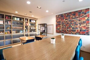 A modern library with bookshelves, a wooden table, and chairs. - Hanting Hotel(train Station Xinhualian Plaza (Yinchuan)