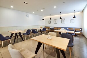 Un comedor moderno con varias mesas y sillas, iluminación empotrada en el techo y obras de arte colgadas en la pared.