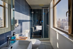 A modern bathroom with a glass shower enclosure, a toilet, and a sink with a soap dispenser. - Hanting Hotel(train Station Xinhualian Plaza (Yinchuan)