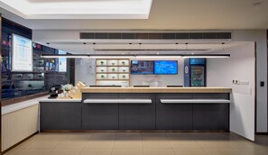 A modern reception area with a digital display, a vending machine, and a plant shelf. - Hanting Hotel(train Station Xinhualian Plaza (Yinchuan)