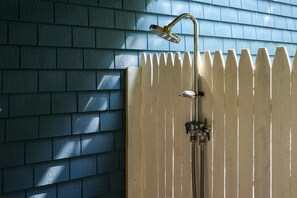 A shower with a handheld showerhead and a wall-mounted faucet, adjacent to a wooden fence. - Coastal Cottage in the heart of Kennebunk, ME (Kennebunk)