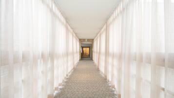 A corridor with patterned flooring and sheer curtains on both sides.