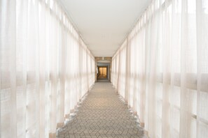 A corridor with patterned flooring and sheer curtains on both sides. - Ji Hotel (Hefei)