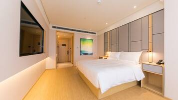 Una habitación de hotel con una cama grande, una mesita de noche y un cuadro en la pared.