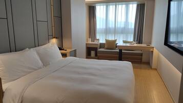 Una habitación de hotel con una cama grande, un escritorio y un ventanal con cortinas.