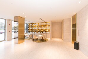 A modern lobby with a seating area, a wall-mounted bookshelf, and an elevator. - Ji Hotel (Hefei)