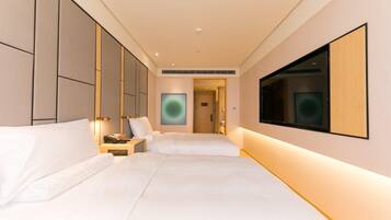 A hotel room with a large bed, bedside tables, a TV, and a door leading to a bathroom.