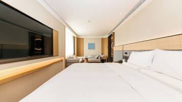 Habitación de hotel con una cama grande, televisor, escritorio y una silla.