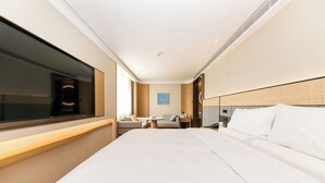Habitación de hotel con una cama grande, televisor, escritorio y una silla.