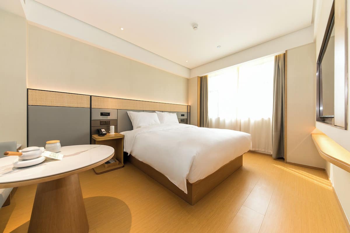Una habitación de hotel con cama, mesita de noche y una pequeña mesa redonda con una silla.