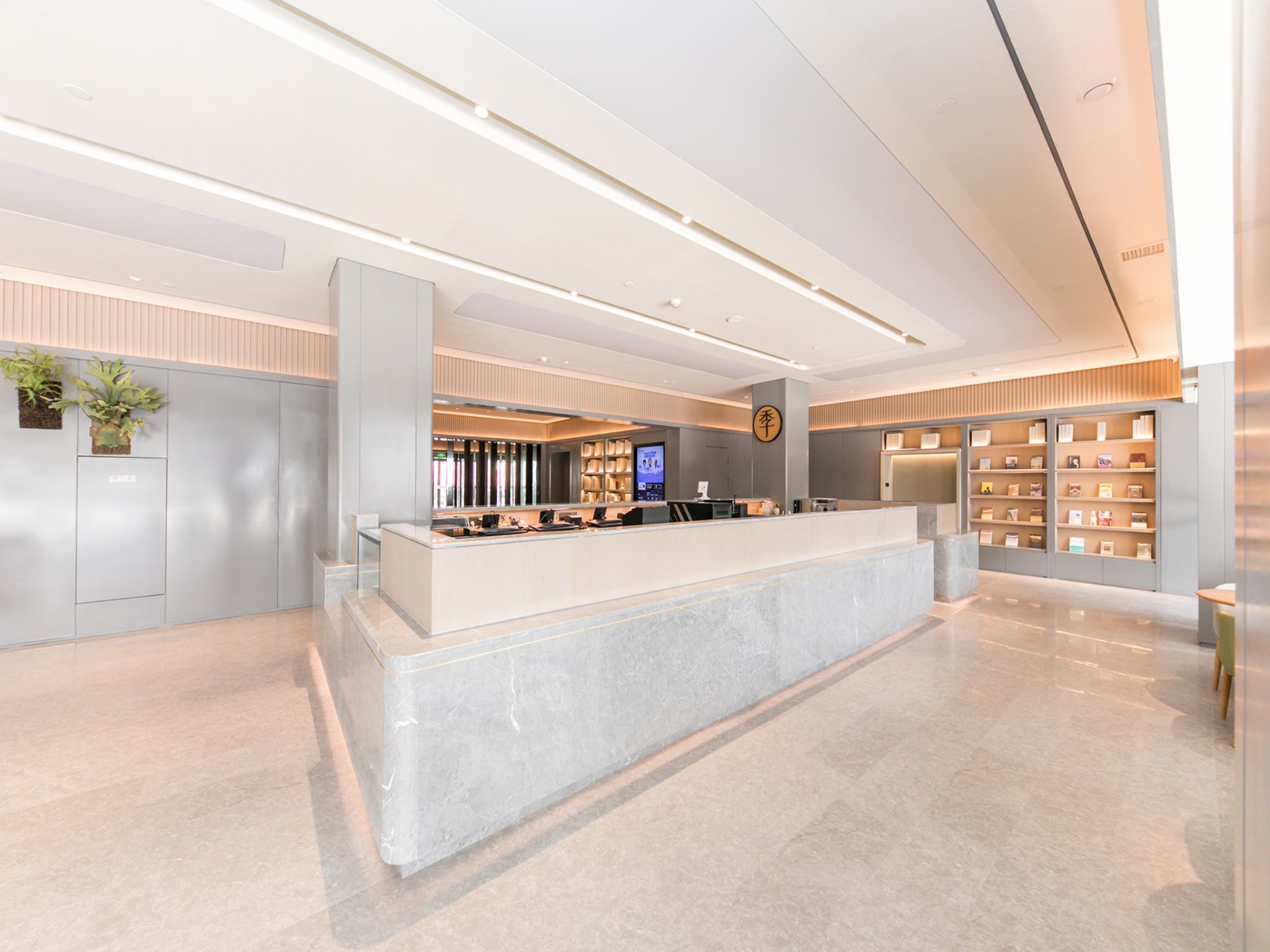 A modern reception area with a marble counter, a digital screen, and a bookshelf.