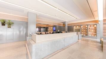 A modern reception area with a marble counter, a digital screen, and a bookshelf.
