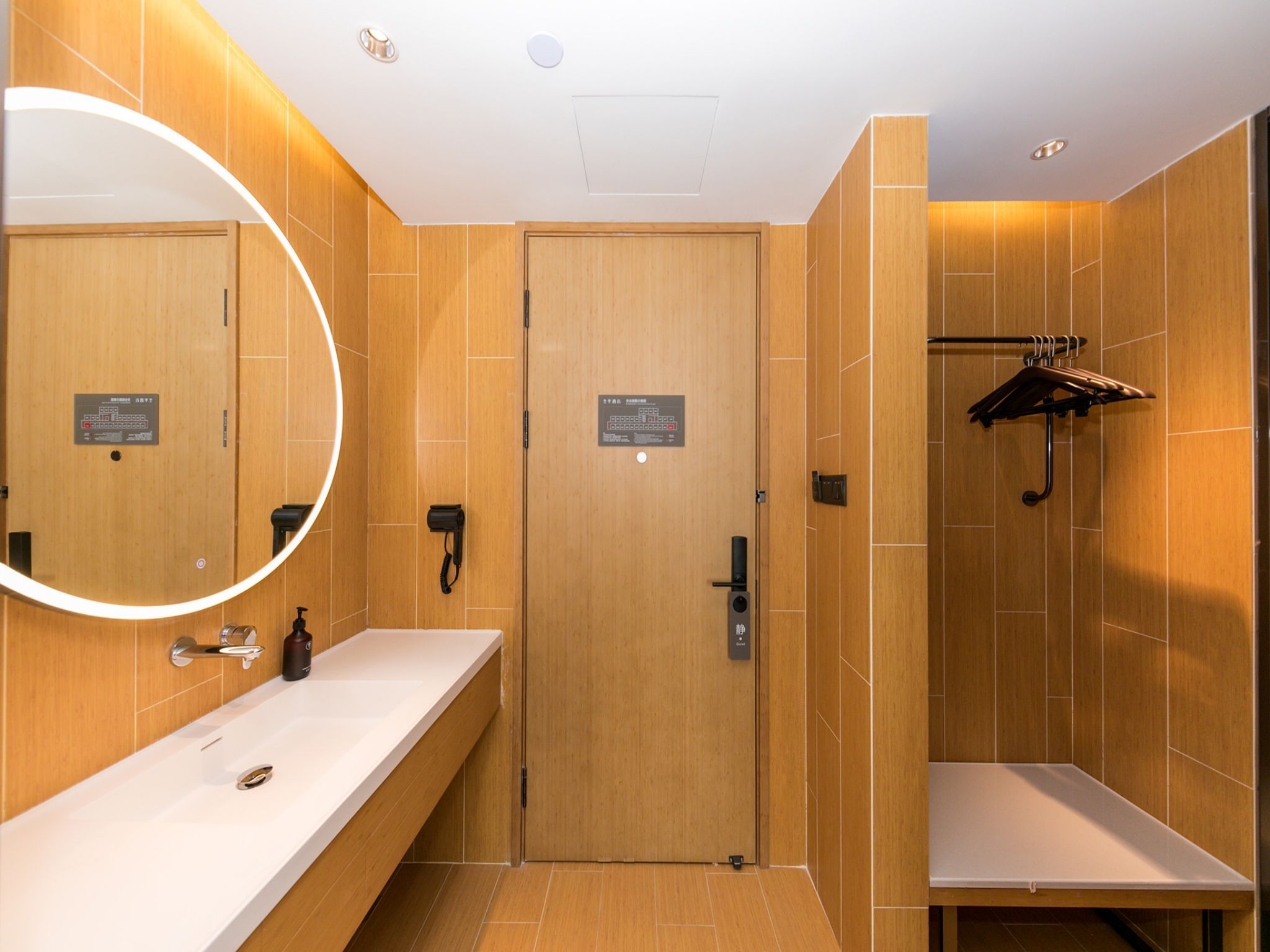 A modern bathroom with wooden walls, a white sink, a mirror, and a shower area.