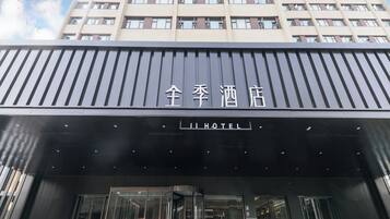 La entrada de un hotel con fachada moderna, destacando un cartel con caracteres chinos y la palabra 'HOTEL' en inglés.