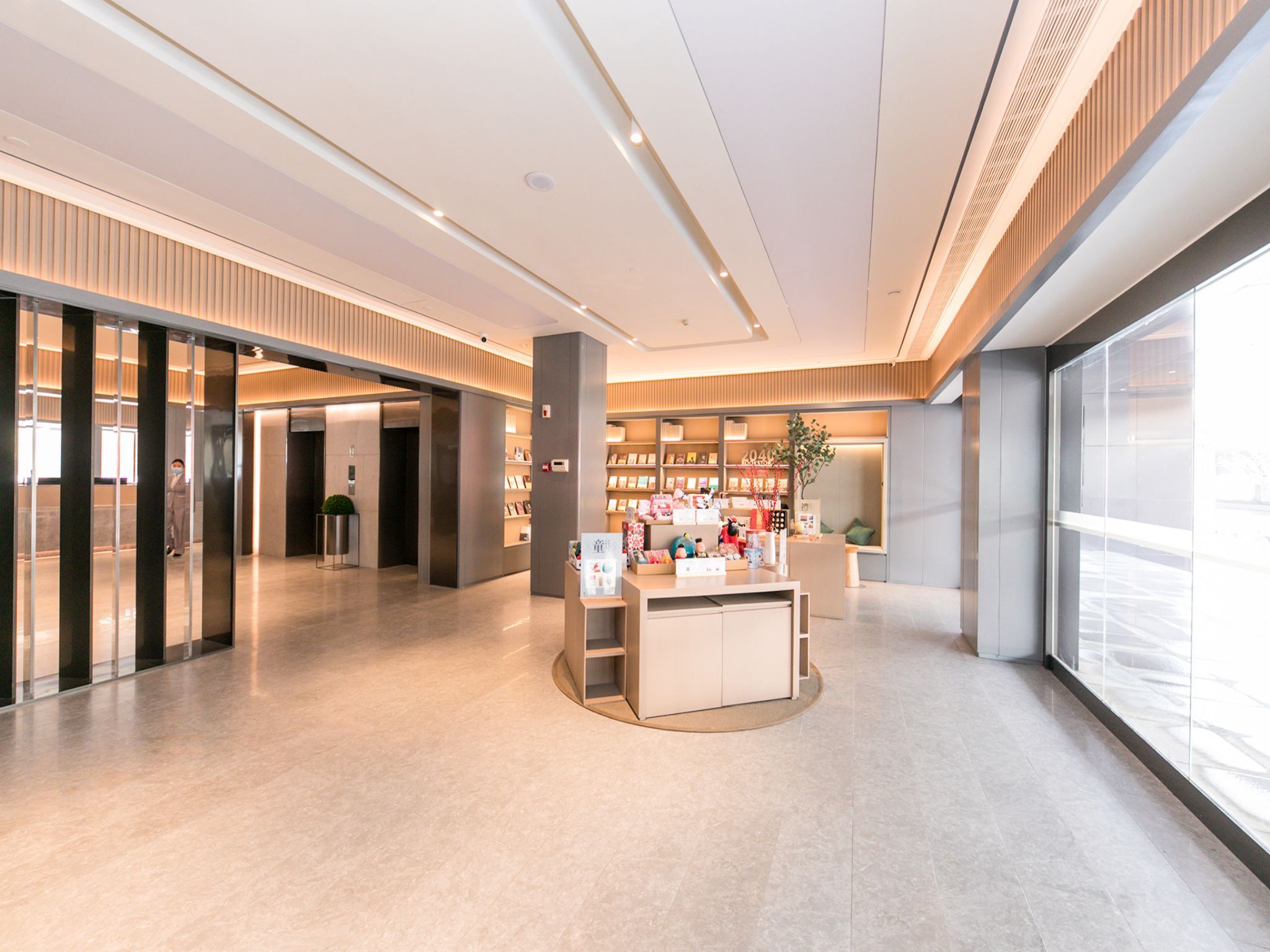 A modern interior with a reception desk, bookshelves, and a large window.