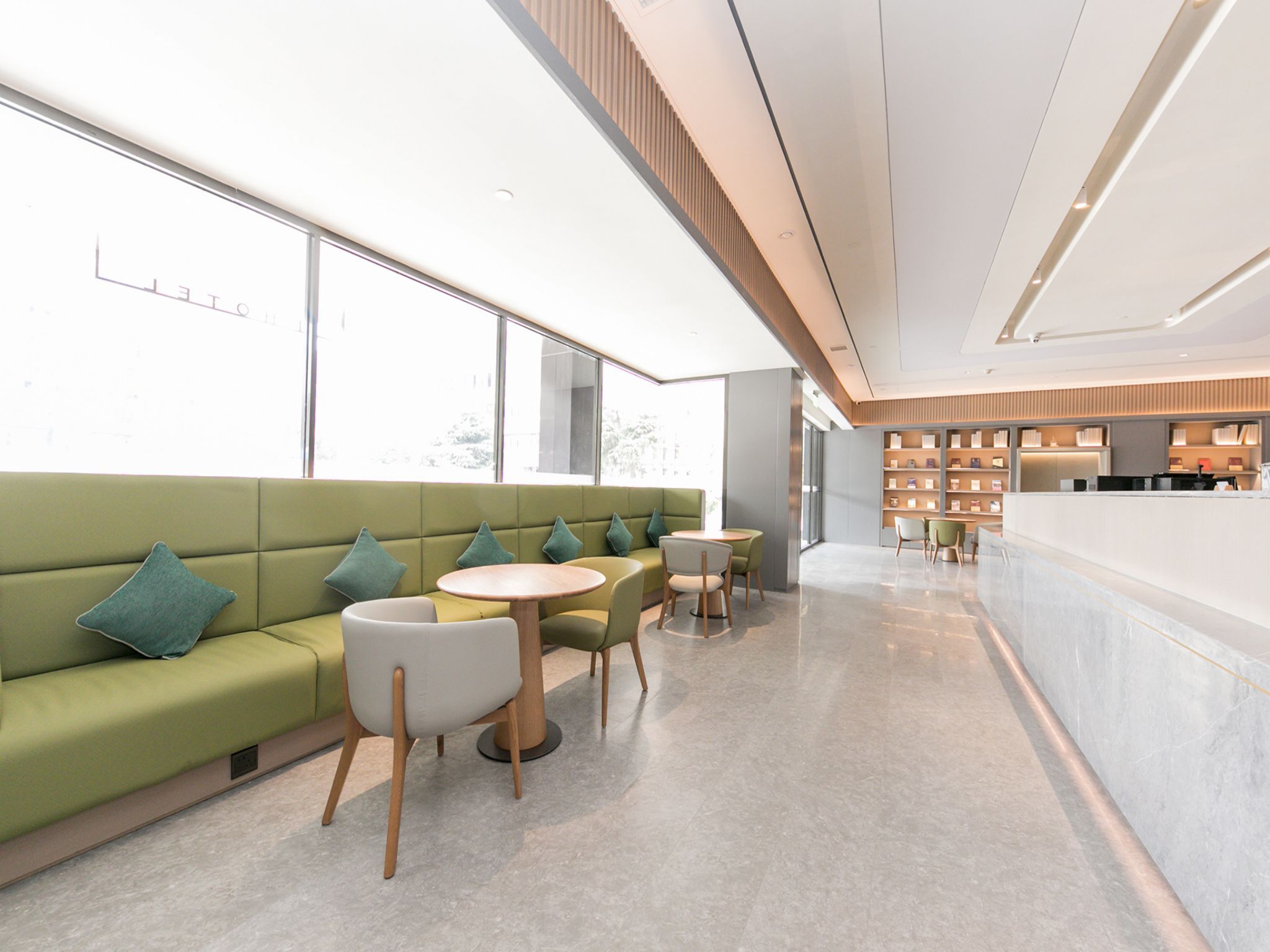 A modern interior with a green sofa, round tables, and a reception desk.