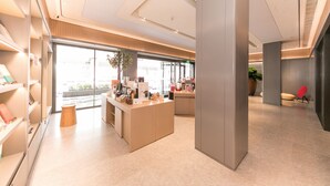 A modern reception area with a central desk, a potted plant, and a red chair. - Ji Hotel (Zhengzhou)