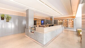A modern reception area with a marble counter, a digital display, and a bookshelf. - Ji Hotel (Zhengzhou)