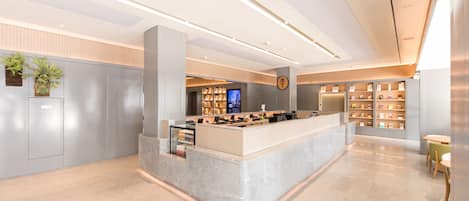 A modern reception area with a marble counter, a digital display, and a bookshelf.