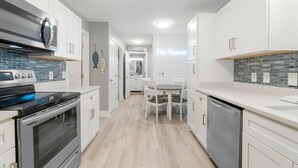 A modern kitchen with white cabinetry, a black stove, and a tiled backsplash. - Completely Remodeled Beach Getaway – Walk to Beach (Panama City Beach)