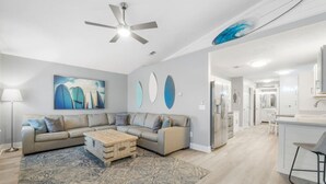 A modern living room with a sectional sofa, a coffee table, and a ceiling fan. - Completely Remodeled Beach Getaway – Walk to Beach (Panama City Beach)