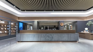 A modern reception area with a marble counter, shelving units, and a digital display. - Ji Hotel (Wenzhou)