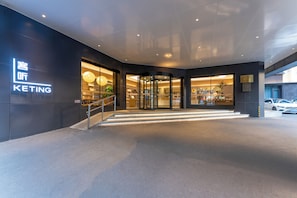 A hotel entrance with a modern design, glass doors, and a staircase leading inside.