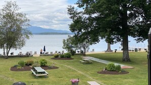 Un patio sul lago con tavoli da picnic, sedie e vista sul lago e sulle montagne.
