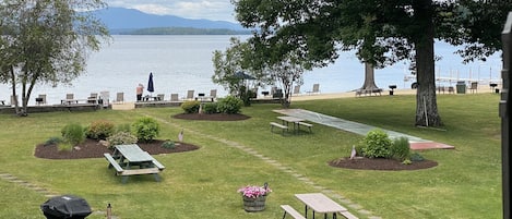 En uteplats vid sjön med picknickbord, bänkar och utsikt över vattnet.