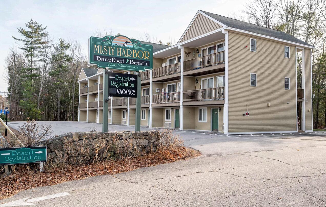 A multi-story building with a sign indicating 'MIS'Y HARBOR Resort Registration' and 'VACANCY'.