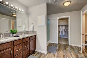 Un baño moderno con un lavamanos de mármol, armarios de madera y un espejo grande.